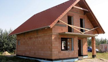 Stavba tehlového rodinného domu so sedlovou strechou.