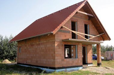Stavba tehlového rodinného domu so sedlovou strechou.
