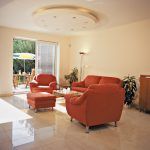 Interiér obývacej izby je ladený v teplých farebných tónoch – od jemnej béžovej a marhuľovej až po sýte červenkasté čerešňové drevo či výraznú terakotovú farbu sedačky.