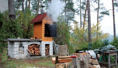 Samostatne stojaci kozub s grilom vo väčšej vzdialensoti od domu má najmenej jednu veľkú výhodu - možno ho postaviť aj s udiarňou. Dym neobťažuje obyvateľov domu.