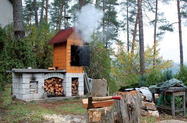 Samostatne stojaci kozub s grilom vo väčšej vzdialensoti od domu má najmenej jednu veľkú výhodu - možno ho postaviť aj s udiarňou. Dym neobťažuje obyvateľov domu.