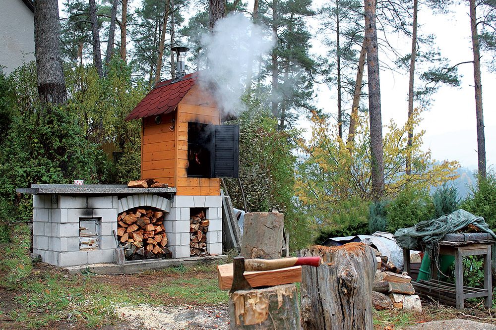 Samostatne stojaci kozub s grilom vo väčšej vzdialensoti od domu má najmenej jednu veľkú výhodu - možno ho postaviť aj s udiarňou. Dym neobťažuje obyvateľov domu.