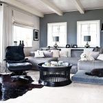 Sivá farba na stenách a sedačke dominuje obývačke. Napriek tomu miestnosť nepôsobí tmavo ani pochmúrne, keďže dostatok svetla dnu privádzajú biele drevené okná s kovovými kľučkami.