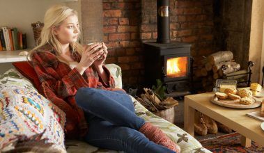 Young woman relaxing by fire with hot drink