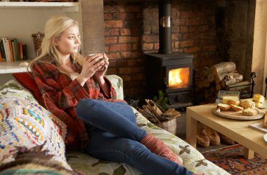 Young woman relaxing by fire with hot drink