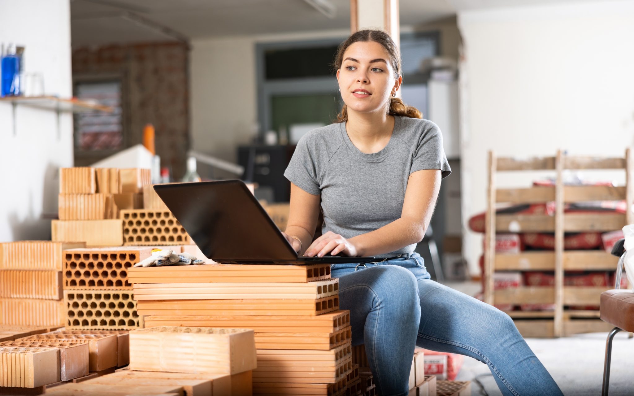 Young,Caucasian,Woman,Designer,Sitting,On,Brick,Stack,In,Construction